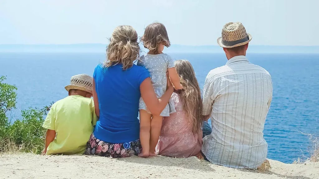 Familia sentada de espaldas frente al mar, símbolo de estabilidad y futuro con planes de ahorro a largo plazo.